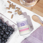 GleeFull Over 30 Hormone Support bottle with blueberries and a glass of water on a marble surface.