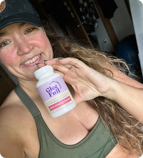 Woman holding a bottle of Glee Full supplements in an indoor setting